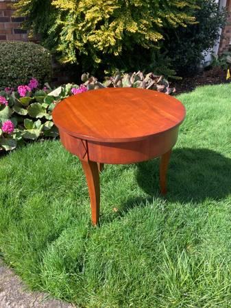 Round solid wood side table with curved legs and carved detail.